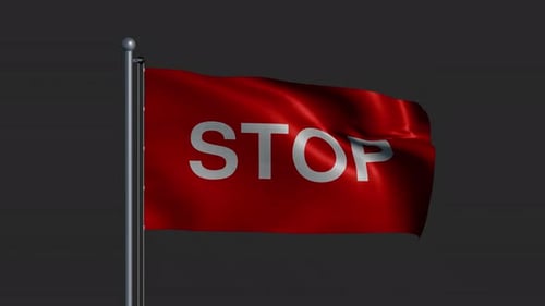 A Flag with the Word STOP Fluttering in the Wind on a Flagpole