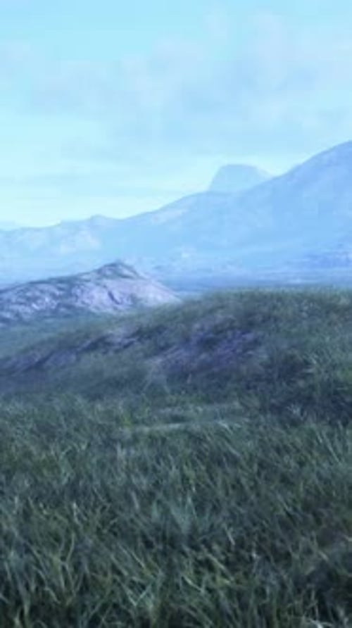 A Scenic View of a Vast Grassy Field with Majestic Mountains in the Backdrop