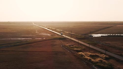 Aerial tracking shot of a transport truck that navigates a straight road, forging ahead towards the