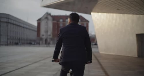 Man In Business Attire Biking By The Nykredit Crystal Building