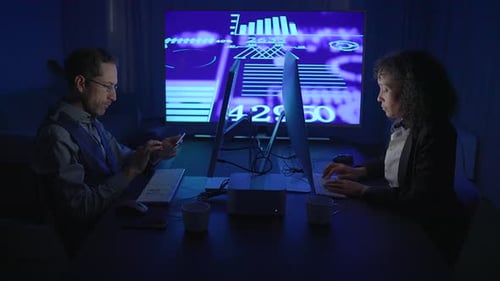Data Analysts Typing at Computers in Dark Office
