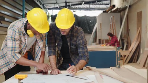 Men Reviewing Blueprint in Workshop