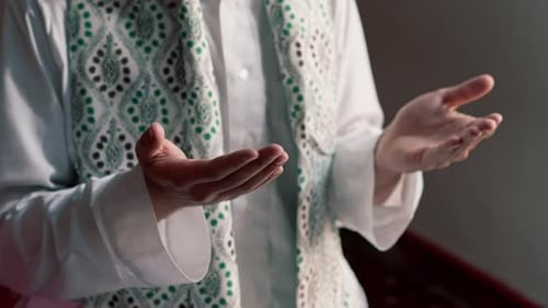 Close-up shot of a Muslim man's hands praying on his knees during Ramadan in Islamic temple