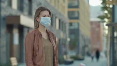 Woman Wearing Mask Stands on Urban Street