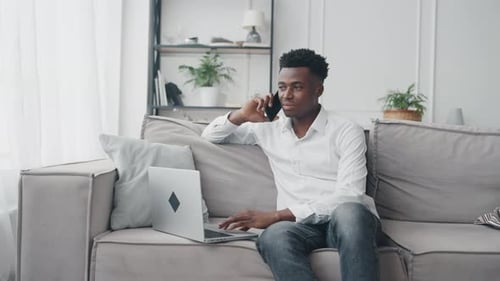 Man on Phone with Laptop Indoors