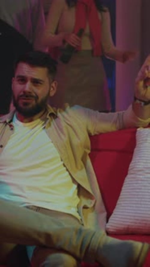 Disbelieving Man Watches Vibrant Party Surroundings Uncertain Individual Reacts to Lively Neon Dance