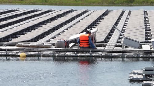 Schwimmendes Solarpanel auf dem Teich. Der Arbeiter wartet und überprüft schwimmende Photovoltaikmodule.