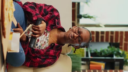 Smiling Woman Sitting on Couch Holding Remote