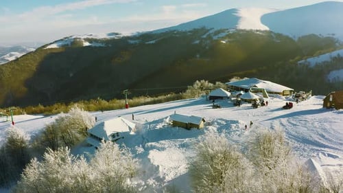 Alte Skistation an einem verschneiten Berghang mit vielen Menschen auf Skiern und Snowboards