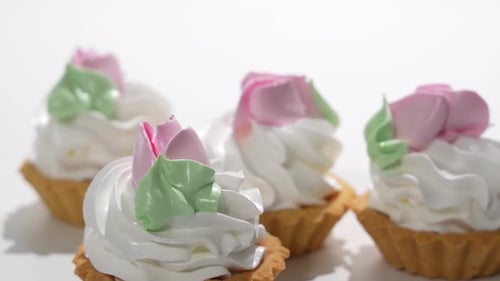 Four cupcakes with pink and green frosting and a flower design on top