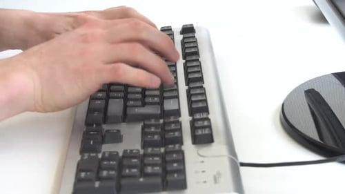 Hands Typing on a Silver Keyboard in Office