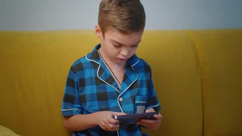Child Plays on Smartphone Indoors at Home