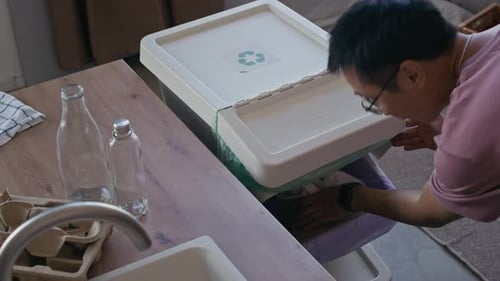 Man sorting recyclables at home in kitchen