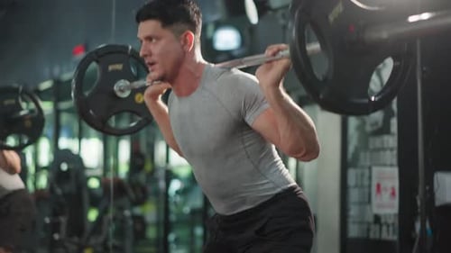 Caucasian sportsman slowly lift up weight machine barbell in stadium.