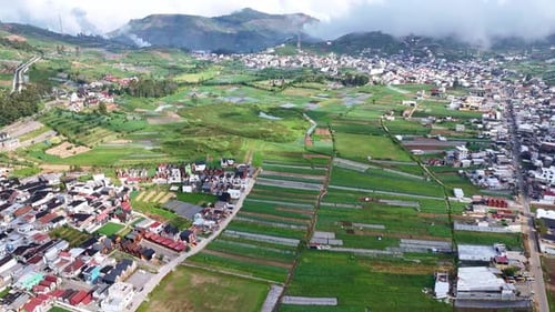 Beautiful panoramic shot of cultivated farmlands and a mountain town under a clear blue sky.