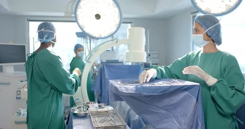 Diverse female and male surgeons in masks preparing operating theatre for surgery, slow motion