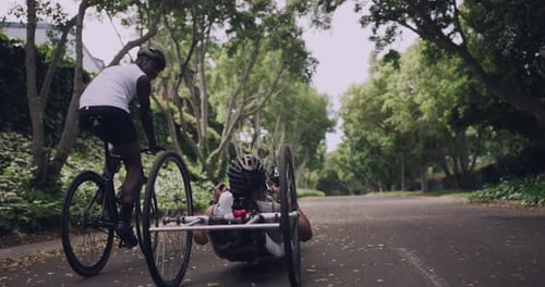Man and Indeterminate Gender Biking on a Tree Lined Road