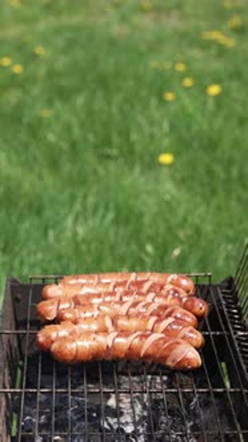 Juicy sausages frying on the grill. Sausages with tasting crust. Barbecue cooking. Vertical video