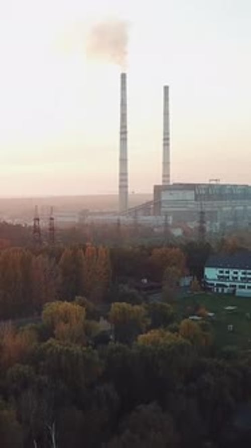 power plant with two pipes is located on the outskirts of the city on the bank of river.