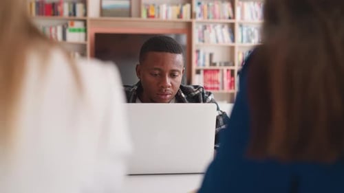 Focused Young Adult Studying with Laptop Indoors