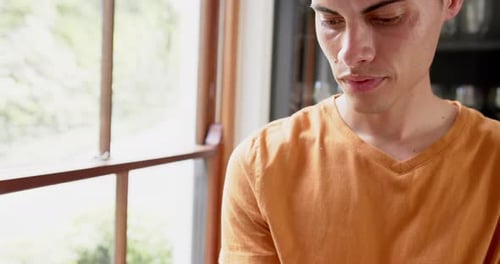 Young Man Looks Out Window with Cell Phone