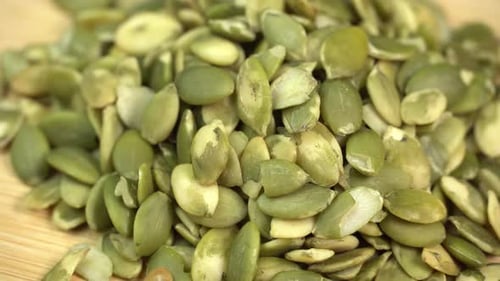 Green Pumpkin Seeds on Wooden Surface, Close-Up