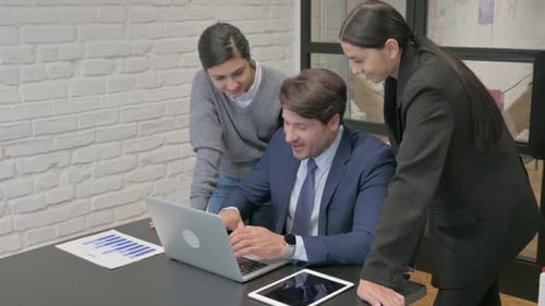 Business Team Collaborating Over Laptop in Modern Office