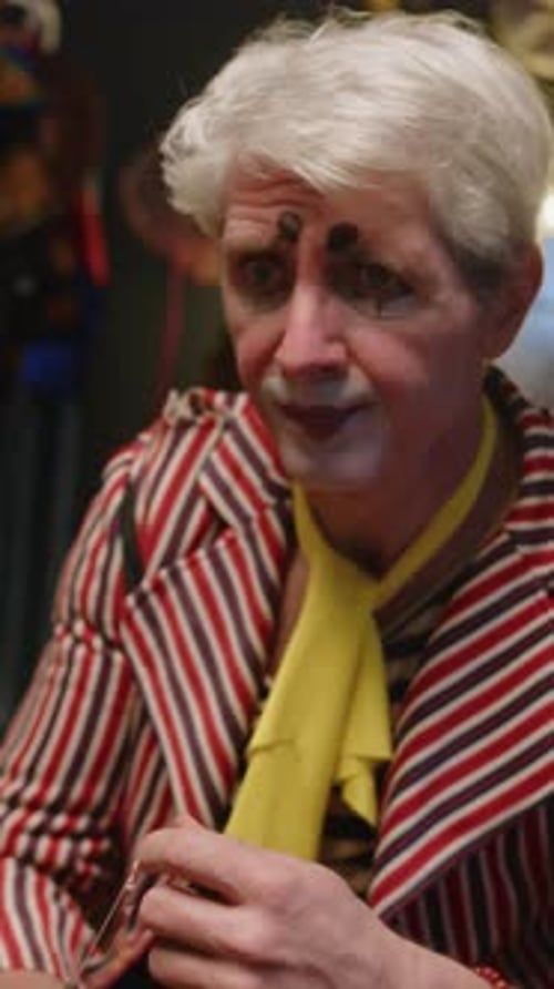 Person Putting on Clown Costume with Red Nose