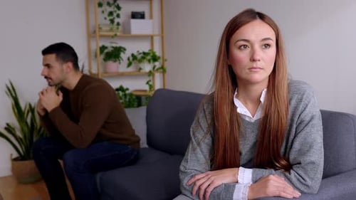 Sad Couple Sitting Apart on Sofa Indoors