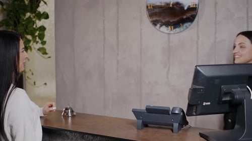 Female guest goes to the hotel reception, rings the bell and talks to the hotel administrator