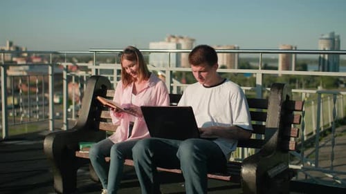 Adultos jóvenes que estudian al aire libre con un pintoresco fondo urbano