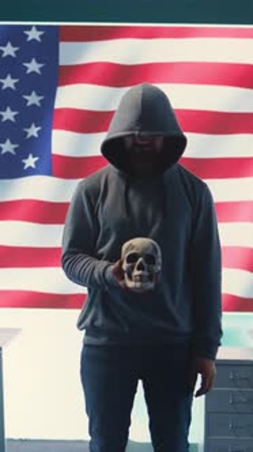 Vertical Video American Man in a Dark Hood Making Death Threats with Human Skull Concept