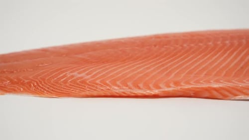 A piece of red fish fillet is shown on a white background
