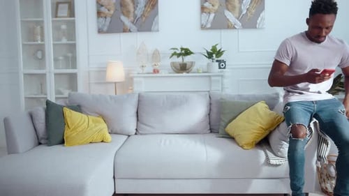 A Man Relaxes on a Stylish Couch Scrolling Through His Phone