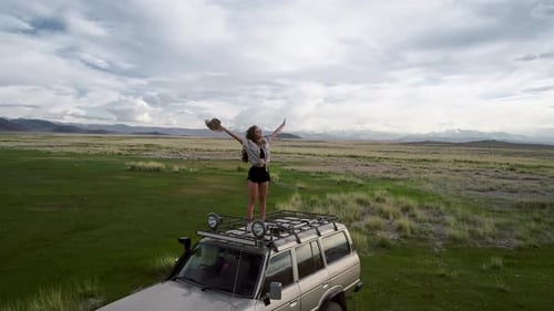 Young Woman Posing on SUV in Rural Landscape