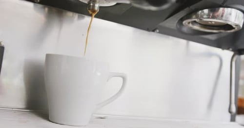 Nahaufnahme einer funktionierenden Kaffeemaschine, die im Café frischen Kaffee in die Tasse gießt