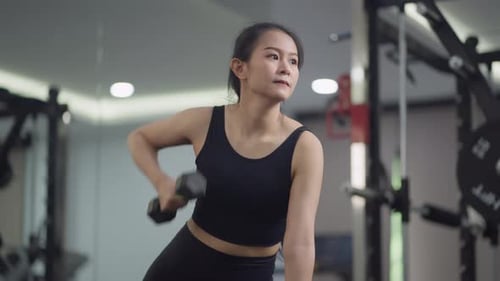 Focused woman lifting dumbbell weights in gym