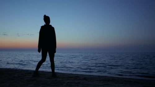 Unbekannte Yogafrau trainiert Yoga an der Küste bei Sonnenuntergang im wunderschönen Abendhimmel