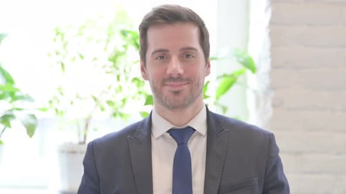 Portrait of Young Businessman Smiling at Camera in Office