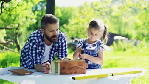 Père avec une petite fille à l'extérieur, fabriquant un nichoir en bois