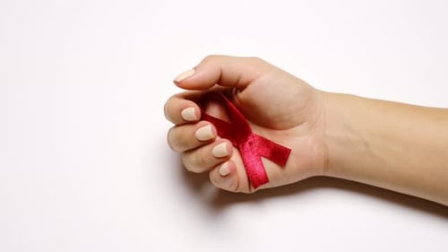 Hand Holding a Red Ribbon for Cause