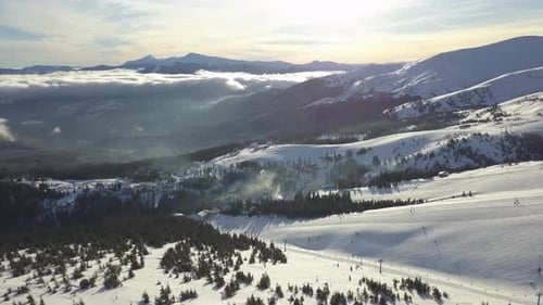 Aerial view of snow-covered mountains with clouds and sunset light