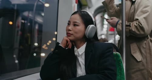 Cute Asian Girl Enjoying Night City Sitting Next to Window of Fast Moving Train Commuting Back Home