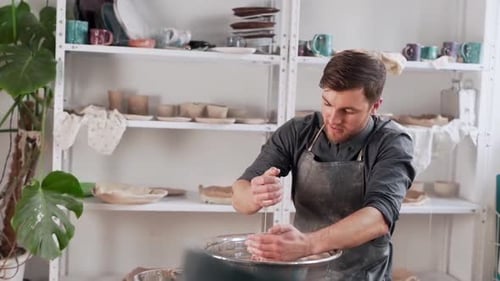 Man Shaping Clay on Pottery Wheel in Studio