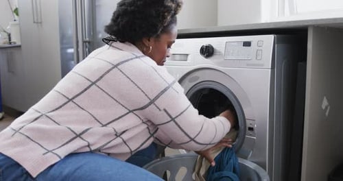 Woman Loading Clothes into Washing Machine at Home