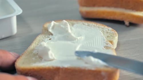 Knife Spreading Butter on a Piece of Bread Close Up View