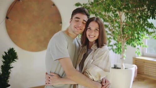 Smiling Young Couple Embraces Indoors