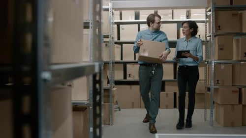 Female Inventory Manager Shows Digital Tablet Information to a Worker Holding Cardboard Box, They T