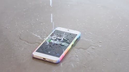 Slow motion water drops falling onto the screen of a mobile cell phone