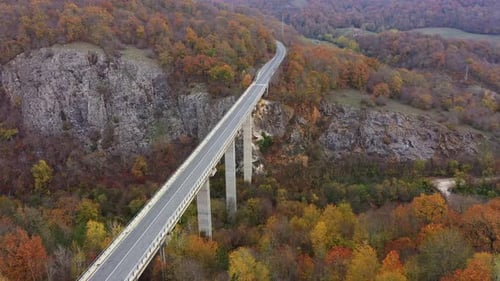 Aerial view of big viaduct of highway over the river in the mountain at autumn